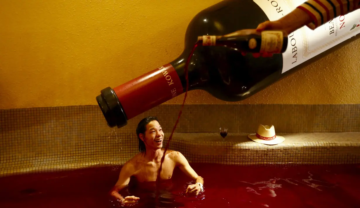 Seorang pria saat sedang mandi di bak air panas dengan air berwarna i anggur di resor spa Hakone Kowaki-en Yunessun selama acara Beaujolais Nouveau Day di Hakone barat Tokyo, Jepang (19/11). (REUTERS/Thomas Peter)