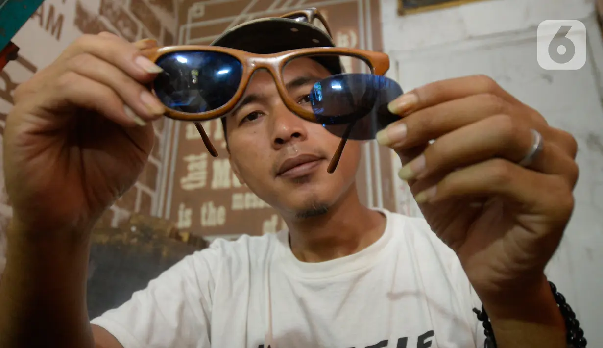 Perajin Yuyud Wahyudi (39) menyelesaikan pembuatan frame kacamata dari limbah kayu bekas di Urat Kayu, Pondok Benda, Pamulang, Tangsel, Kamis (8/10/2019). Kacamata kayu hasil buatannya tersebut dijual dengan harga Rp 300 ribu hingga Rp 1,2 juta per buah. (merdeka.com/Dwi Narwoko)