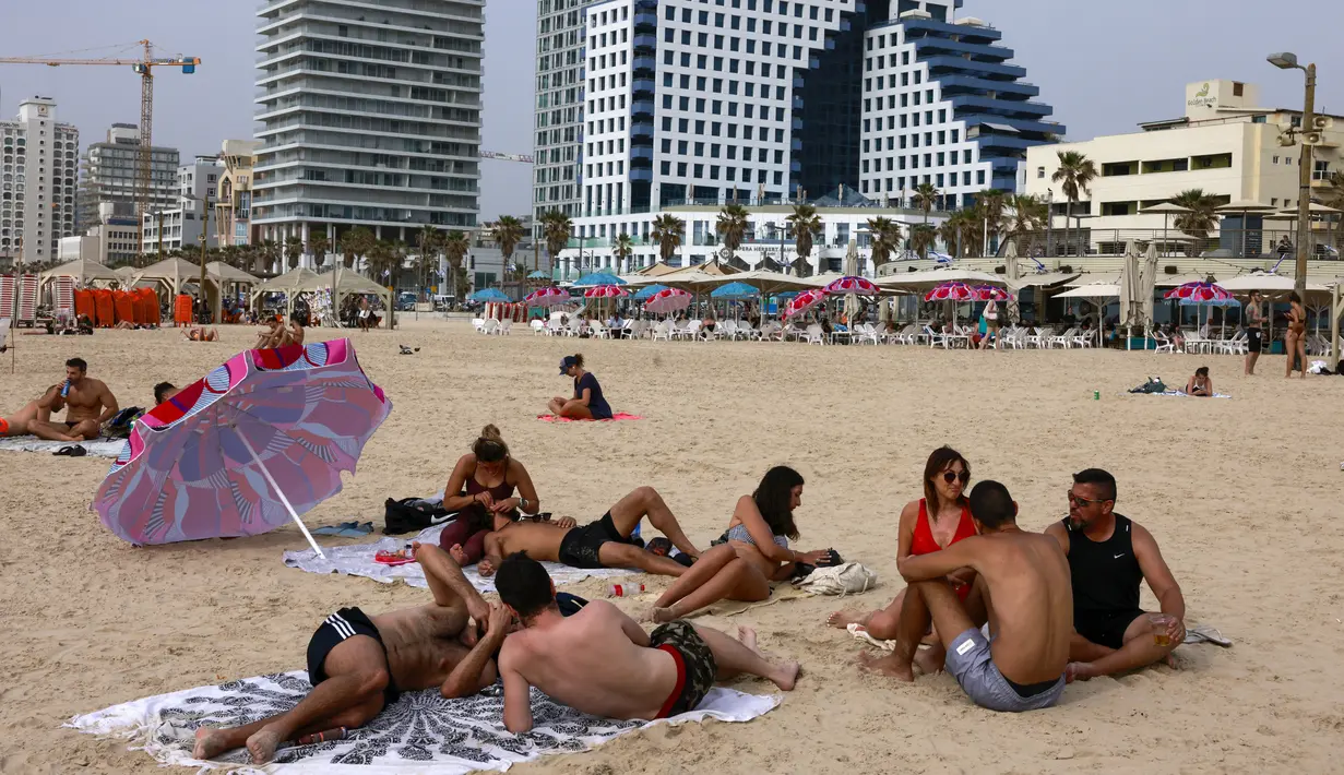 Orang-orang bersantai di pantai di kota pesisir Israel Tel Aviv (19/4/2021). Sebanyak 81 persen warga di atas usia 16 tahun mendapat vaksin, dan berdampak pada penurunan angka rawat inap dan penyebaran virus corona. (AFP/menahem kahana)