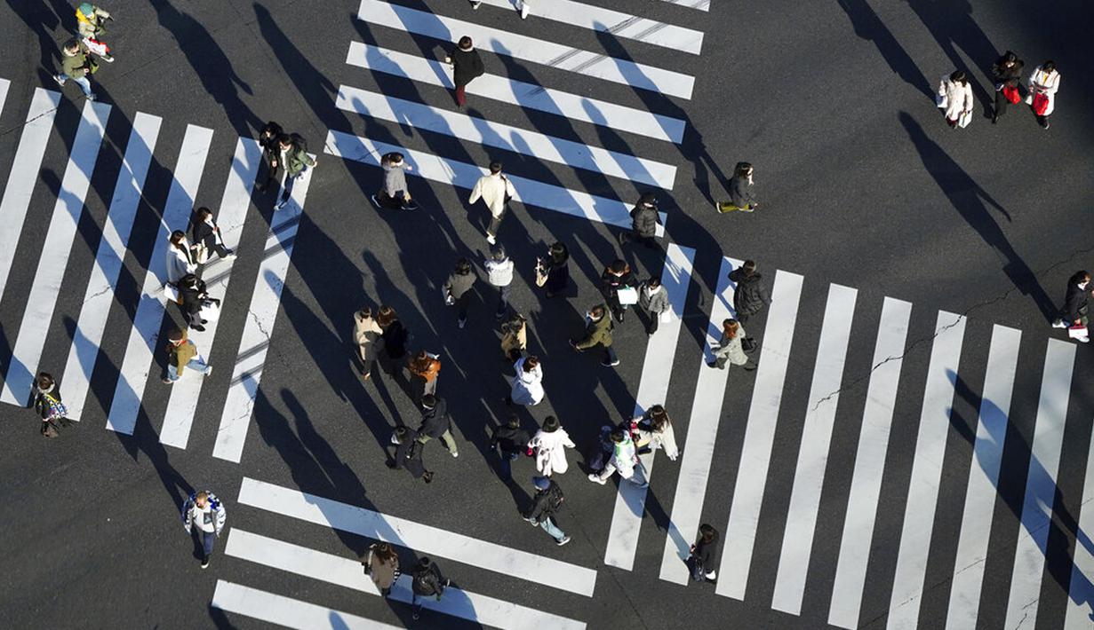 Orang-orang yang memakai masker untuk membantu mengekang penyebaran COVID-19 menyeberangi jalan di Tokyo, Jepang, 29 Desember 2021. Kepala Rumah Sakit Pusat Sumida Dr Kuniaki Kojima memperkirakan saat ini gelombang keenam COVID-19 di Jepang sudah dimulai. (AP Photo/Eugene Hoshiko)