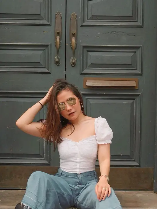 Pemeran film Danur ini tampil menawan dengan blouse cantik berwarna puti yang dipadukan dengan celana jeans. Menggunakan kacatama dengan lensa gelap ala retro, penampilannya semakin trendi.(Liputan6.com/IG/@prillylatuconsina96)