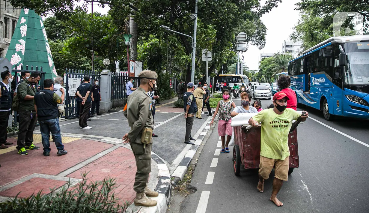 Petugas Satpol PP berjaga di depan Gereja Katedral, Jakarta, Kamis (24/12/2020). Gereja Katedral Jakarta memberlakukan aturan pembatasan jemaat yang hadir saat misa Natal hanya 20 persen dari kapasitas gereja untuk menekan penyebaran virus COVID-19. (Liputan6.com/Faizal Fanani)