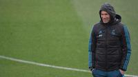 Pelatih Real Madrid, Zinedine Zidane tersenyum saat menyaksikan para pemainnya berlatih di Madrid, Spanyol (10/4). Madrid akan bertanding melawan Juventus pada leg kedua perempat final Liga Champions di Stadion Bernabeu. (AFP Photo/Gabriel Bouys)