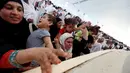 Jemaah haji perempuan melempar jumrah sambil menggendong anak saat ibadah haji di Mina, Arab Saudi (12/09). Lemparan batu pada jumroh menjadi simbol kesadaran untuk membebaskan diri dari sifat Qarun. (REUTERS/Ahmed Jadallah)