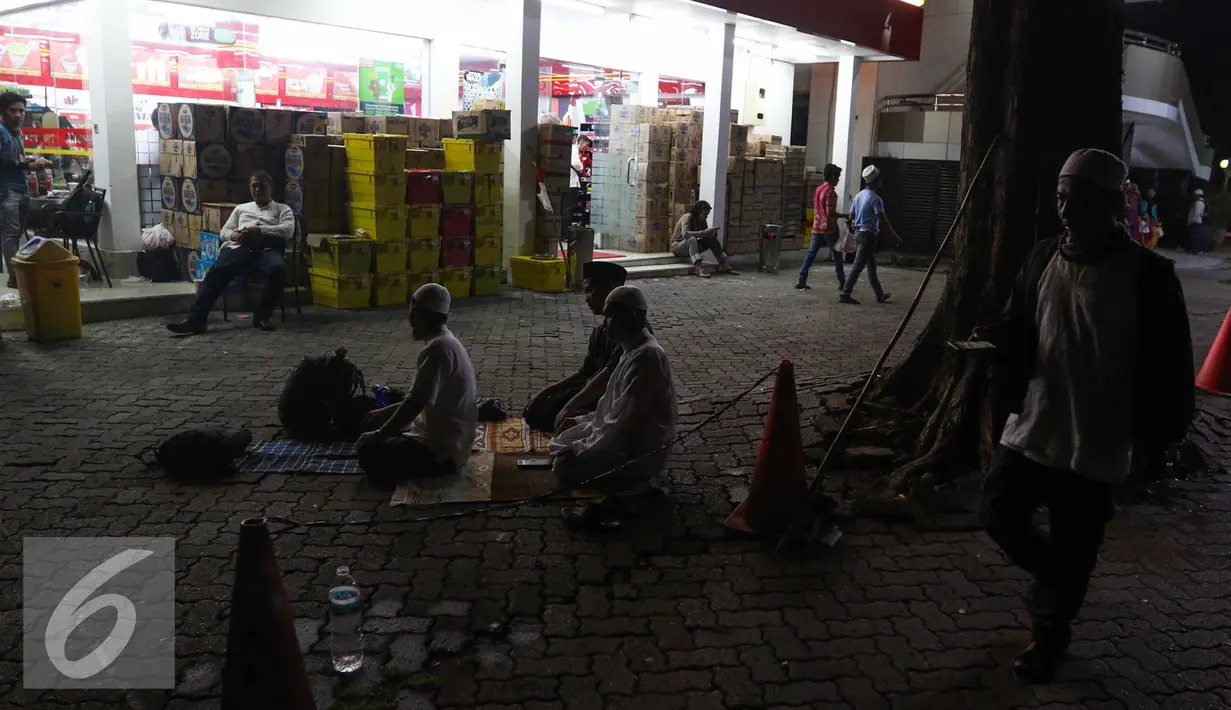 Sejumlah peserta Aksi Damai 4 November melaksanakan Salat Magrib berjamaah di depan mini market di Stasiun Gambir, Jakarta, Jumat (4/11). (Liputan6.com/Faizal Fanani)