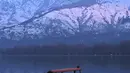 Orang-orang menikmati perjalanan dengan perahu dengan latar belakang pegunungan yang tertutup salju di danau Dal di Srinagar (11/1/2022). Daya tarik keindahan yang sempurna membuat danau Dal dijuluki sebagai Jewel in the Crown of Kashmir atau Srinagar Jewel. (AFP/Tauseef Mustafa)