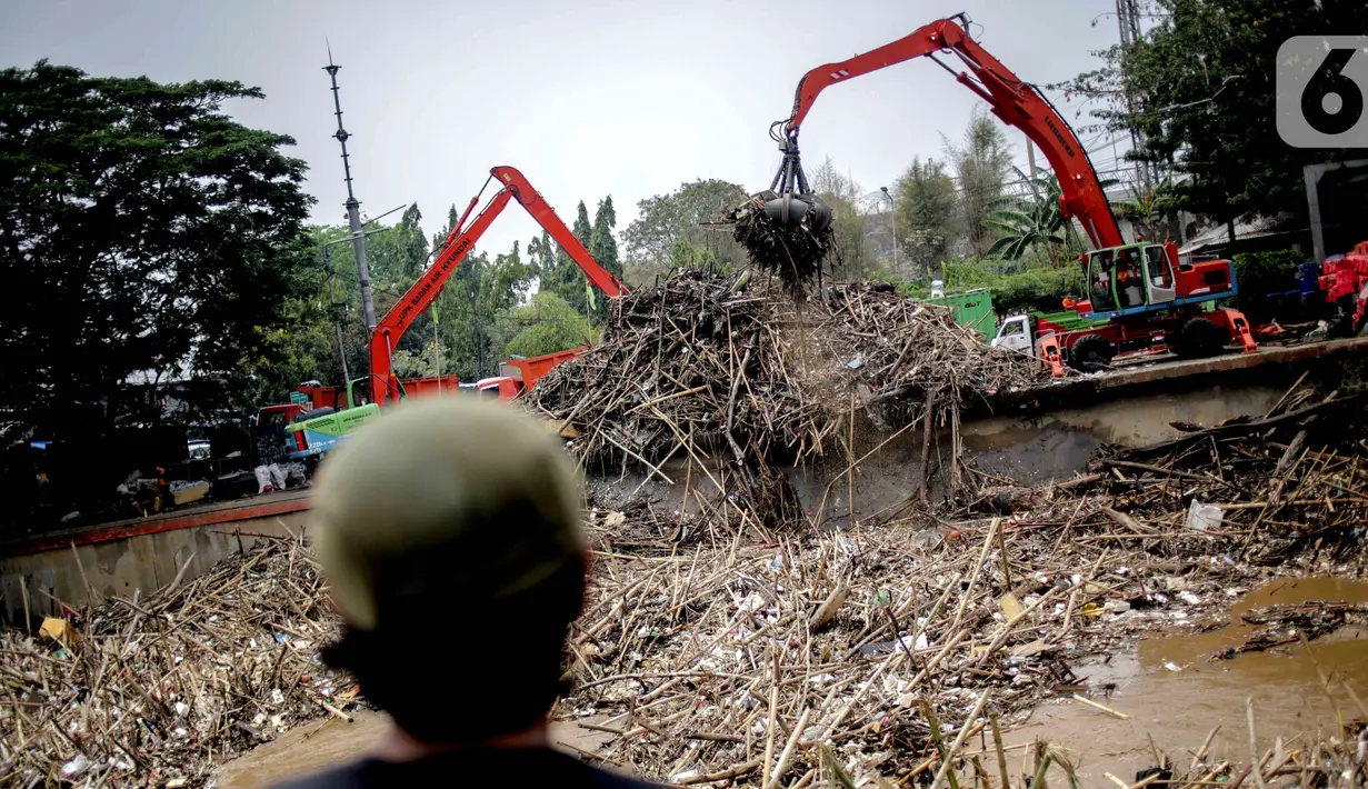 Petugas dibantu alat berat membersihkan sampah kayu dan bambu yang tersangkut di Pintu Air Manggarai, Jakarta, Rabu (9/10/2019). Sekitar 80 ton sampah diangkut menggunakan alat berat. (Liputan6.com/Faizal Fanani)