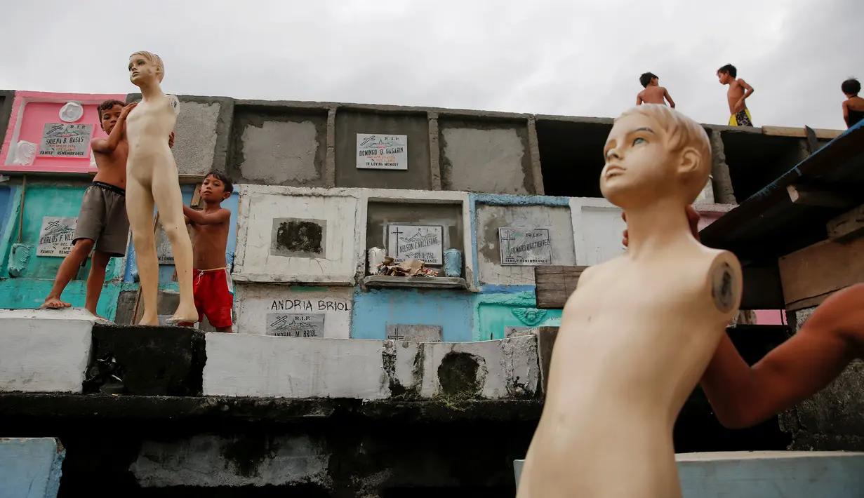 Sekelompok anak bermain manekin diatas kuburan di North Cemetery, Manila, Filipina, Minggu (16/10). Pemakaman ini dihuni banyak keluarga yang berprofesi seperti perawat makam dan penggali kuburan. (Reuters/ Damir Sagolj)