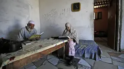 Seorang pria bersama istrinya membaca Al-Quran selama bulan suci Ramadan di Kota Gaza, Palestina, Jumat (1/5/2020). (MOHAMMED ABED/AFP)