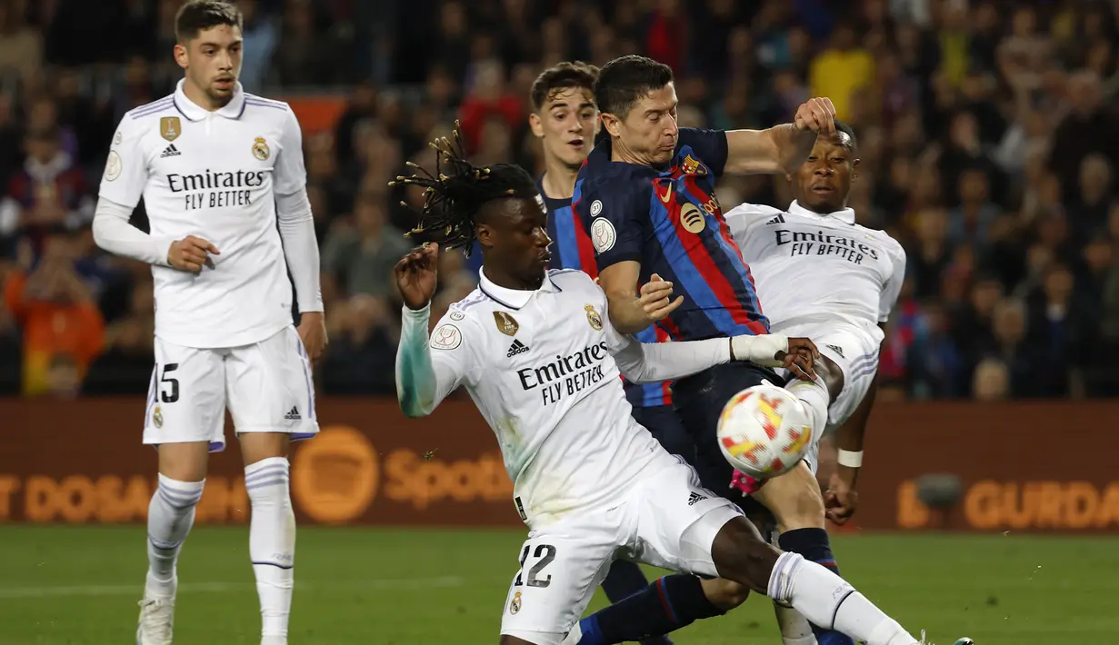 Striker Barcelona, Robert Lewandowski (tengah) diadang dua pemain Real Madrid, Eduardo Camavinga (kiri) dan David Alaba pada laga leg kedua semifinal Copa del Rey 2022/2023 di Camp Nou Stadium, Barcelona, Kamis (6/4/2023) dini hari WIB. (AP Photo/Joan Monfort)