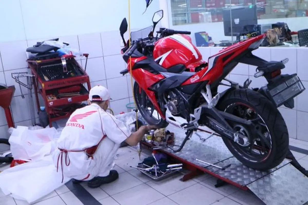 Mekanik bengkel Honda sedang melakukan service sepeda motor.