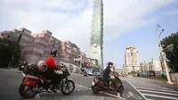 Warga memakai masker untuk melindungi diri dari penyebaran COVID-19 saat melewati Gedung Taipei 101 di Taipei, Taiwan, Sabtu (15/5/2021). Pandemi COVID-19 di Taiwan naik ke level tiga. (AP Photo/Chiang Ying-ying)