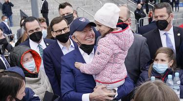 Presiden Amerika Serikat Joe Biden menggendong seorang gadis saat bertemu dengan pengungsi Ukraina pada kunjungan ke PGE Narodowy Stadium di Warsawa, Polandia, 26 Maret 2022. (AP Photo/Evan Vucci)