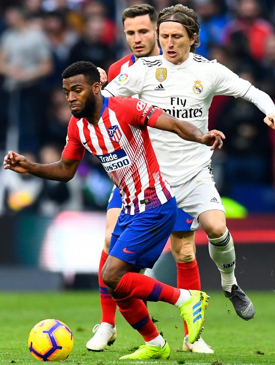 Gelandang Real Madrid, Luka Modric berusaha merebut bola yang dibawa gelandang Atletico Madrid, Thomas Lemar selama pertandingan lanjutan La Liga Spanyol di stadion Wanda Metropolitano (9/2). Real Madrid menang 3-1. (AFP Photo/Gabriel Bouys)