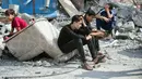 Anak-anak Palestina duduk di reruntuhan bangunan yang hancur akibat serangan udara Israel di Kamp Nuseirat, Jalur Gaza, Senin (16/10/2023). (AP Photo/Hatem Moussa, File)