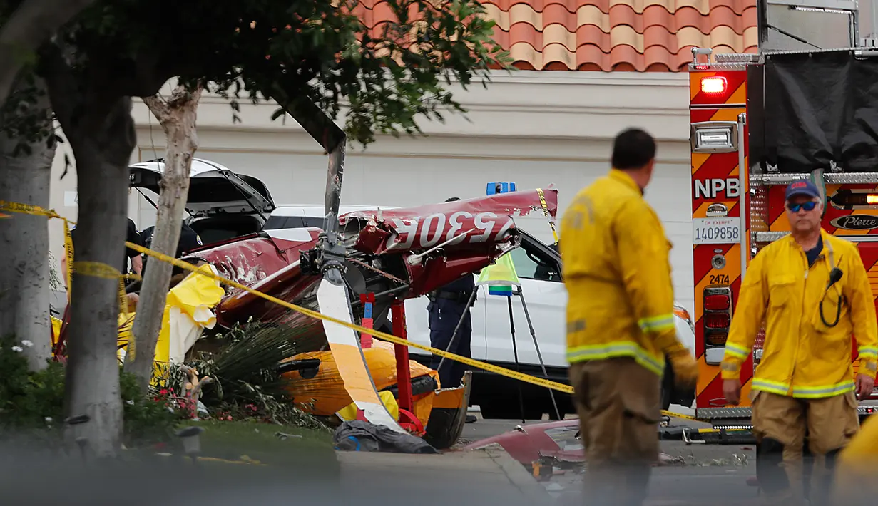 Polisi menyelidiki helikopter yang jatuh menghantam sebuah rumah di Newport Beach, California, Selasa (30/1). Lima orang terlibat kecelakaan termasuk empat orang yang berada di helikopter dan satu pejalan kaki. (Allen J. Schaben/Los Angeles Times via AP)