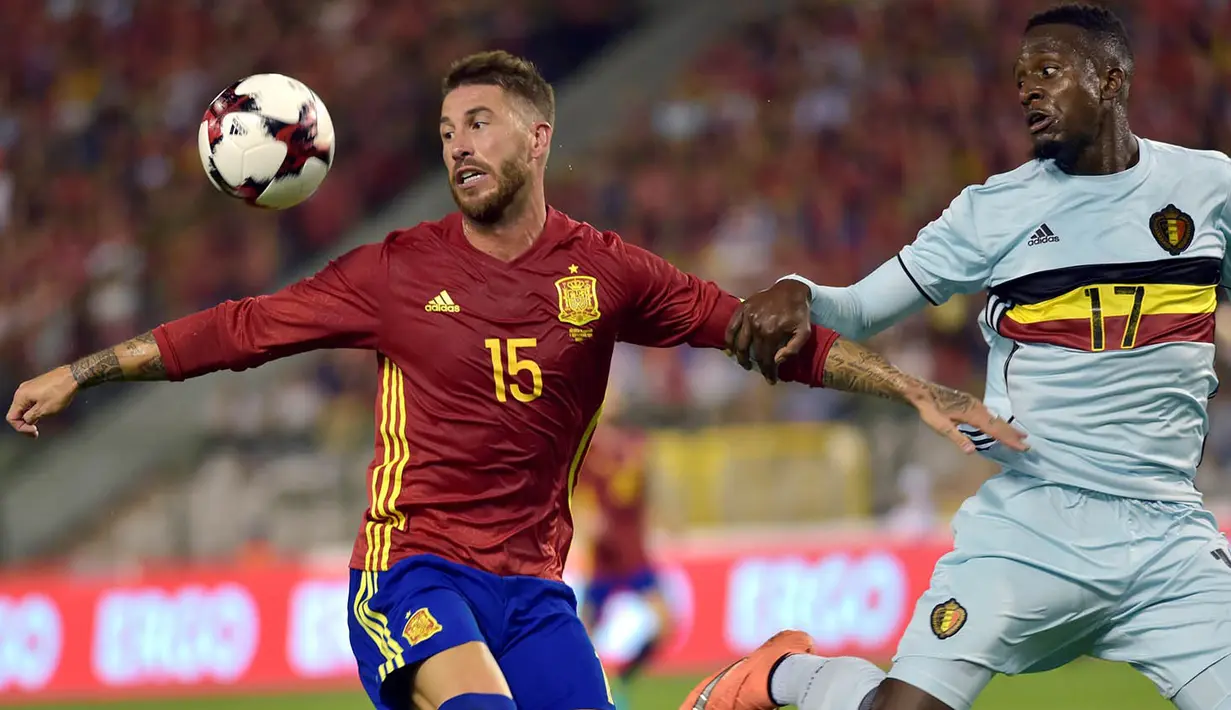 Bek Spanyol, Sergio Ramos, berusaha menahan pergerakan striker Belgia, Divock Origi. Spanyol menguasai jalannya laga dengan penguasaan bola 61 persen. (Reuters/Eric Vidal)