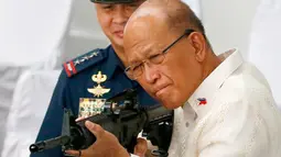 Menhan Filipina Delfin Lorenzana mencoba senapan serbu yang dihibahkan China, Manila, Filipina (5/10). Ribuan senapan serbu senilai US$ 3,3 juta (Rp 43,7 miliar) akan diserahkan seluruhnya ke Kepolisian Nasional Filipina (PNP). (AP Photo/Bullit Marquez)