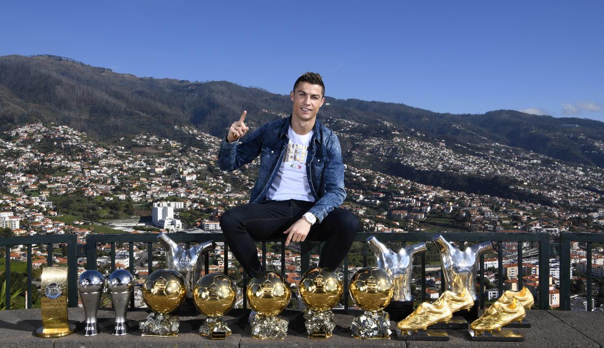 Bintang Real Madrid, Cristiano Ronaldo, berpose di depan trofi di kampung halamannya di Madeira, Portugal, Senin (1/1/2018). Pemain bernomor punggung tujuh itu memamerkan 15 trofi individual yang ia raih sebagai pemain terbaik. (AP/CR7 Media)