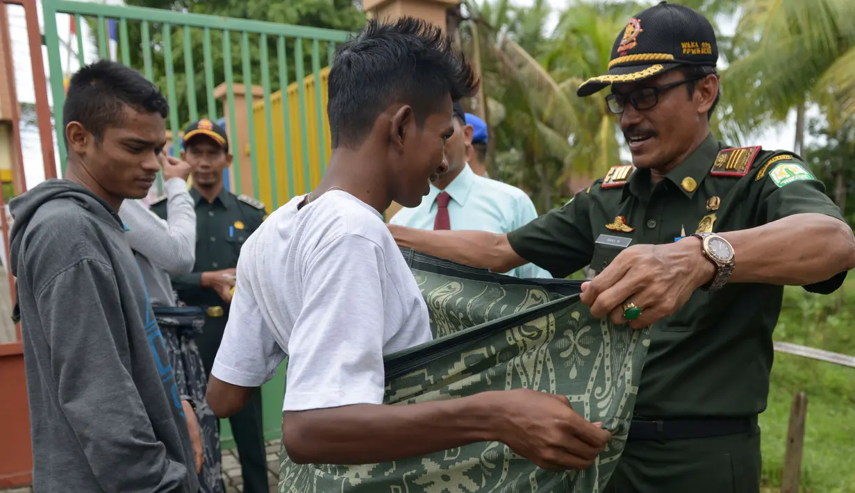 Polisi Syariat Islam memakaikan kain sarung pada warga bercelana pendek saat razia penertiban hukum syariat islam di Banda Aceh, Aceh, Selasa (19/9). Razia digelar sebagai implementasi Qanun Aceh No 11 Tahun 2002. (CHAIDEER MAHYUDDIN/AFP)