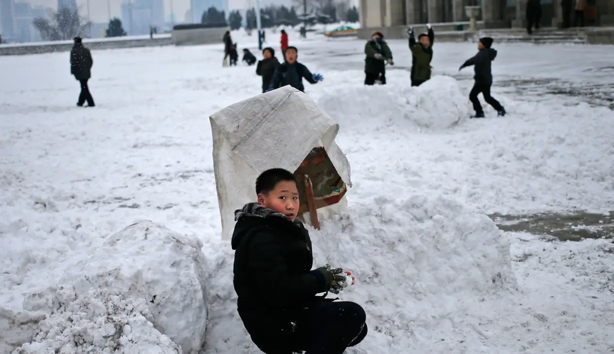 Seorang bocah berlindung selama pertandingan bola salju di Kim Il Sung Square, Pyongyang, Korea Utara, Minggu (16/12). Korea Utara saat ini mulai memasuki musim dingin. (AP Photo/Dita Alangkara)