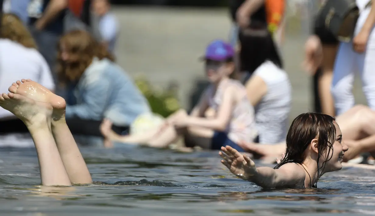 Seorang gadis Rusia berenang di kolam air mancur di Taman Gorky, Moskow (7/6). Memasuki musim panas, sebagian warga Moskow menghabiskan waktu di taman untuk berjemur atau bermain air di kolam air mancur. (AFP Photo/Alexander Nemenov)