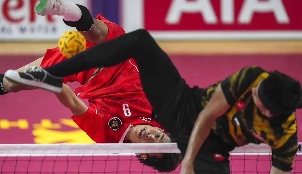 Pemain Tim Sepak Takraw Indonesia, Rusdi (kiri) menendang bola ke arah Tim Sepak Takraw Malaysia pada laga final nomor ganda putra perorangan sepak takraw SEA Games 2023 di Olympic Stadium, Phnom Penh, Kamboja, Senin (15/05/2023). Indonesia berhasil menang dengan skor skor 14-21, 21-16, dan 21-13. (AP Photo/Tatan Syuflana)