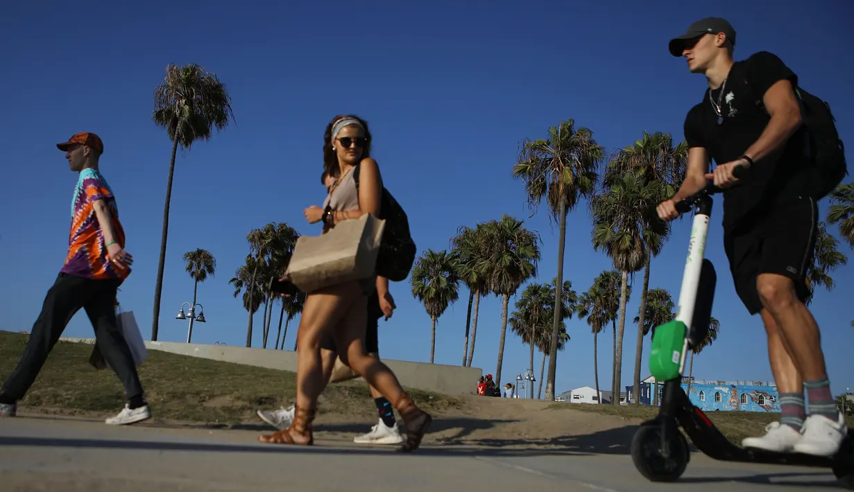 Seorang pria mengendarai Skuter listrik dari startup LimeBike di sepanjang Venice Beach, Los Angeles, 13 Agustus 2018. Anggota Dewan Los Angeles telah mengusulkan pelarangan skuter sampai peraturan dapat diselesaikan. (Mario Tama/Getty Images/AFP)
