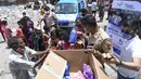 Seorang polisi dan relawan memberikan makanan ringan kepada anak-anak setelah memberikan sampel swab untuk pengujian virus corona Covid-19 di dalam sebuah van di New Delhi, India (1/7/2021).  (AFP/Prakash Singh)