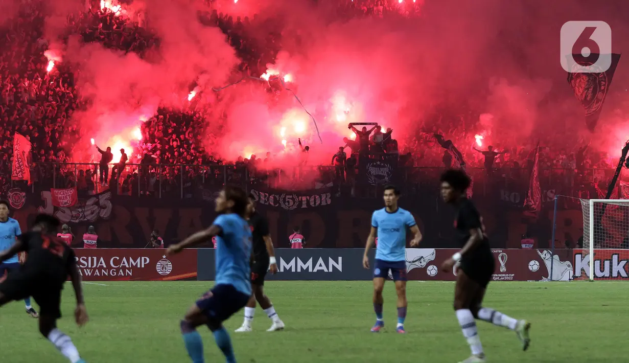 Suporter menyalakan flare saat menyaksikan laga Persija melawan Sabah FC pada laga uji coba internasional di Stadion Patriot Candrabhaga, Kota Bekasi, Minggu (5/6/2022). Pertandingan sepakbola kembali bisa disaksikan secara langsung setelah pemerintah melonggarkan aturan pemakaian masker di luar ruangan. (Liputan6.com/Helmi Fithriansyah)
