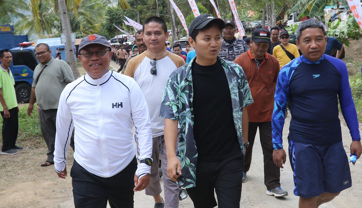 Dirut BPJS Ketenagakerjaan, Agus Susanto dan Bupati Trenggalek, Mochammad Nur Arifin berjalan di Pantai Mutiara, Trenggalek, Jawa Timur, Sabtu (7/9/2019). Bantuan 100 terumbu karang untuk meningkatkan pariwisata di Kabupaten Trenggalek agar ekonomi semakin meningkat. (Liputan6.com/Herman Zakharia)