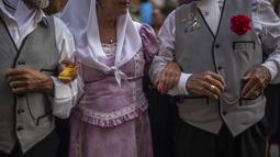 Orang-orang yang mengenakan pakaian tradisional 'chulapo' menari selama perayaan San Cayetano, santo pelindung tenaga kerja dan roti, di lingkungan Lavapies di Madrid, Spanyol, Sabtu (6/8/2022). Festival San Cayetano menandai awal dari serangkaian festival populer di Madrid. (AP Photo/Manu Fernandez)