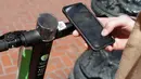Seorang pria bernama Jack Handlery menggunakan aplikasi di ponsel pintarnya untuk menggunakan skuter bermotor di San Francisco (17/4). (AP/Jeff Chiu)