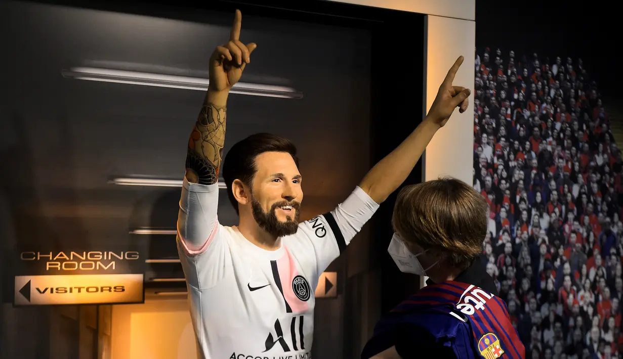Seorang tim potret museum lilin Madame Tussauds Berlin, Karen Fries (kanan) memperbaiki jersey baru Paris Saint-Germain (PSG) pada patung lilin Lionel Messi di Berlin. (11/7/2021). Messi resmi bergabung dengan PSG dari Barcelona setelah menandatangani kontrak dua tahun. (AFP/Tobias Schwarz)