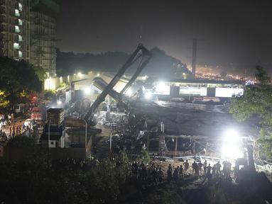 Tim penyelamat mencari korban luka di bawah papan reklame yang runtuh akibat hujan lebat dan hujan lebat, di Mumbai, India, Senin (13/5/2024). (AP Photo/Rafiq Maqbool)