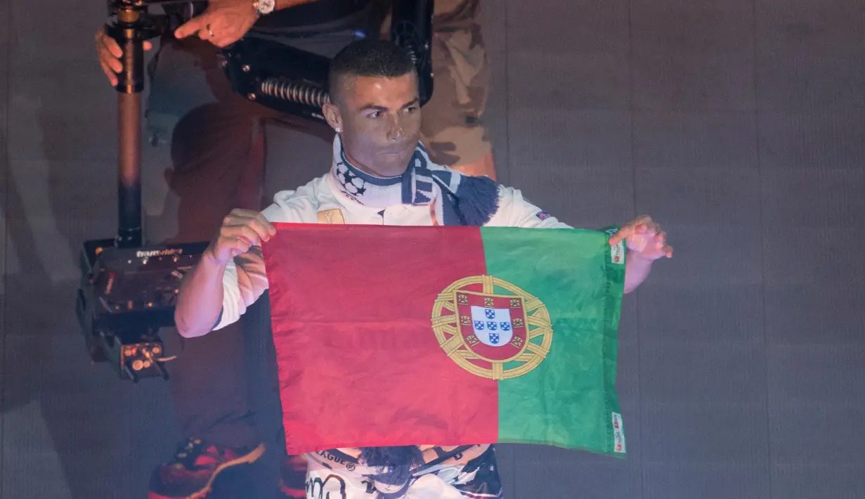 Cristiano Ronaldo memegang bendera Portugal saat  merayakan keberhasilan Real Madrid raih gelar ke-12 Liga Champions di Stadion Santiago Bernabeu, Madrid (4/6). Real Madrid menjadi juara usai mengalahkan Juventus 4-1. (AFP Photo/Curto De La Torre)