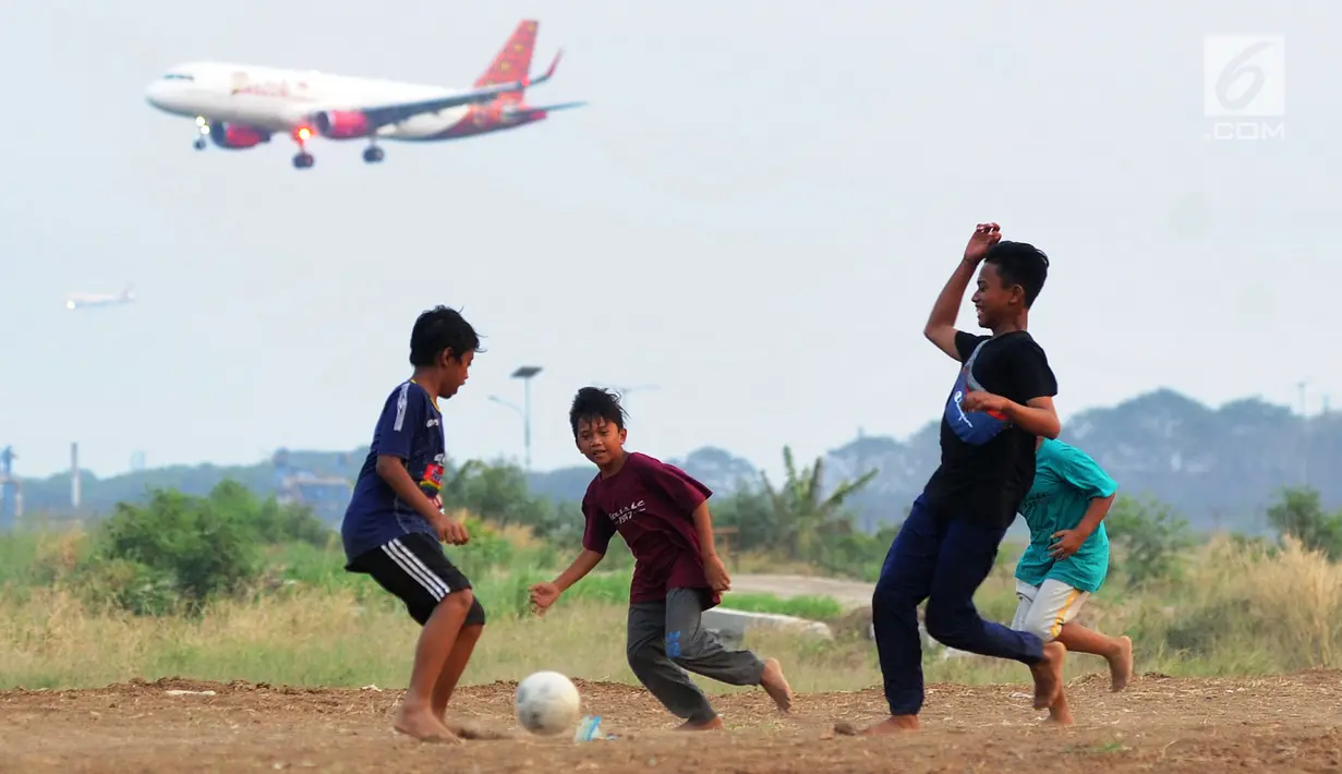 Anak-anak bermain bola di kawasan proyek perluasan landasan pacu atau Runway 3A Bandara Soekarno-Hatta (Soetta), Rawa Bokor, Tangerang, Banten, Selasa (2/7/2019). Mereka memanfaatkan lahan kosong yang belum dikerjakan pihak kontraktor untuk bermain bola. (merdeka.com/Arie Basuki)