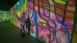 Pengunjung berswafoto dengan karya seniman Austria, Friendensreich Hundertwasser dalam pameran seni proyeksi di galeri l'Atelier des Lumieres di Paris, Prancis (24/4). (AP/Michel Euler)