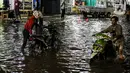 Pengendara sepeda motor mendorong kendaraannya saat melewati banjir di Jalan Ciracas Raya, Jakarta, Jumat (12/8/2022). Hujan lebat yang terjadi sore tadi membuat Jalan Ciracas Raya tergenang air dan kendaraan terjebak banjir. (Liputan6.com/Faizal Fanani)