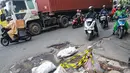 Upaya ini diharapkan dapat mengurangi potensi kecelakaan serta memperlancar mobilitas masyarakat di tengah musim hujan. Tampak dalam foto, sejumlah pengendara melewati kerusakan di Jalan Gedong Panjang, Penjaringan Jakarta Utara, Selasa (3/2/2026). (merdeka.com/Arie Basuki)