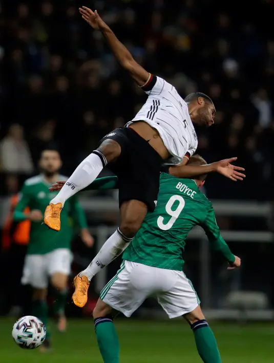 Bek Timnas Jerman, Jonathan Tah melompat saat berebut bola dengan pemain Timnas Irlandia Utara, Liam Boyce pada laga Grup C Kualifikasi Piala Eropa 2020 di Commerzbank Arena, Selasa (19/11/2019). Timnas Jerman sanggup membenamkan Irlandia Utara dengan skor telak 6-1. (AP/Michael Probst)