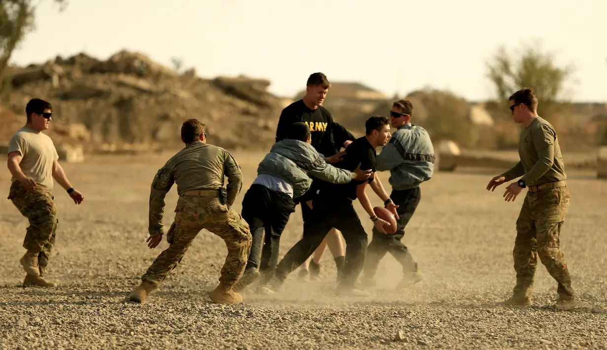 Tentara AS berlari untuk mengumpan bola kepada rekannya saat bermain American Football pada Thanksgiving di dalam pangkalan militer AS di Qayyara, selatan Mosul, Irak (24/141). (REUTERS/Thaier Al-Sudani)