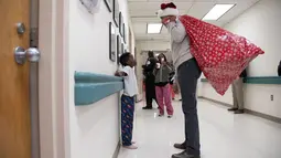 Mantan Presiden AS, Barack Obama mengobrol dengan seorang pasien anak di Children's National Medical Center , Washington, Rabu (19/12). Obama mengunjungi anak-anak yang sedang menjalani perawatan di sana untuk membagikan kado Natal. (Chuck Kennedy / AFP)