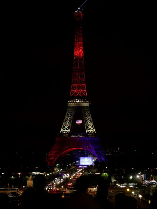 Pengunjung memandangi Menara Eiffel yang disoroti lampu pelangi, Paris, Senin (13/6/2016). Menara yang terkenal dengan romantisme itu memberikan penghormatan untuk korban penembakan brutal di klub malam gay di Orlando, Florida AS. (Thomas SAMSON/AFP)