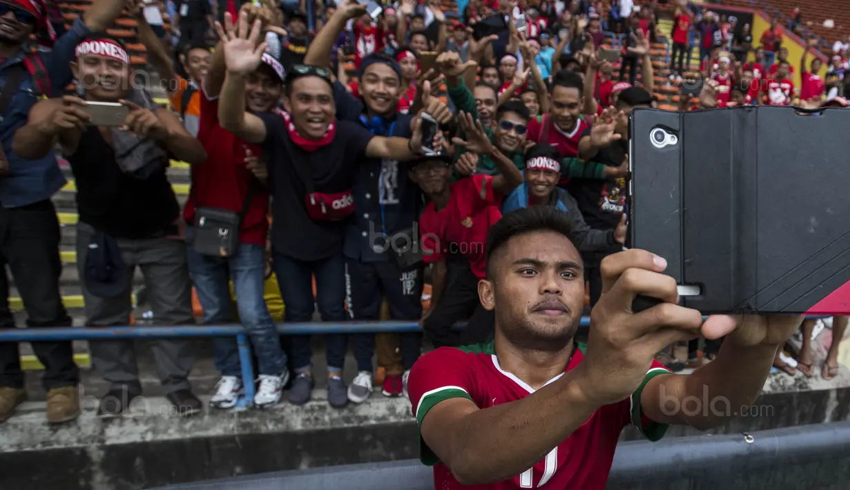 Gelandang Timnas Indonesia, Saddil Ramdani, swafoto bersama suporter usai laga SEA Games melawan Thailand di Stadion Shah Alam, Selangor, Selasa (15/8/2017). Kedua negara bermain imbang 1-1. (Bola.com/Vitalis Yogi Trisna)