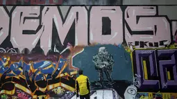 Kevin Belyk melihat karyanya setelah menyelesaikan lukisan mural foto Senator AS Bernie Sanders di taman skateboard Terowongan Leeside di Vancouver, British Columbia (28/1/2021). Foto Bernie Sanders viral dan jadi banyak meme di media sosial (medsos). (Darryl Dyck/The Canadian Press via AP)