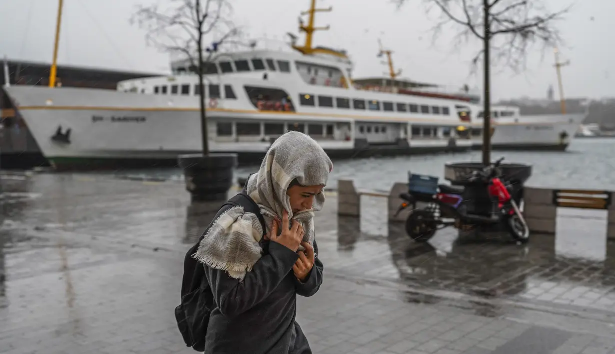 Seorang perempuan berjalan di bawah hujan lebat selama hari badai di Istanbul, Turki, Senin (29/11/2021). Badai kuat melanda Istanbul dan bagian lain dari Turki pada hari Senin, menewaskan sedikitnya empat orang dan menyebabkan kekacauan di kota 15 juta orang, menurut laporan. (AP Photo)