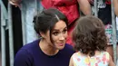 Duchess of Sussex, Meghan Markle menyapa anak kecil saat berjalan di Taman Pemerintah Rotorua, Selandia Baru, Rabu (31/10). Meghan dan Pangeran Harry sedang dalam tur tiga minggu di Australia, Selandia Baru, Tonga, dan Fiji. (Michael Bradley/Pool/AFP)