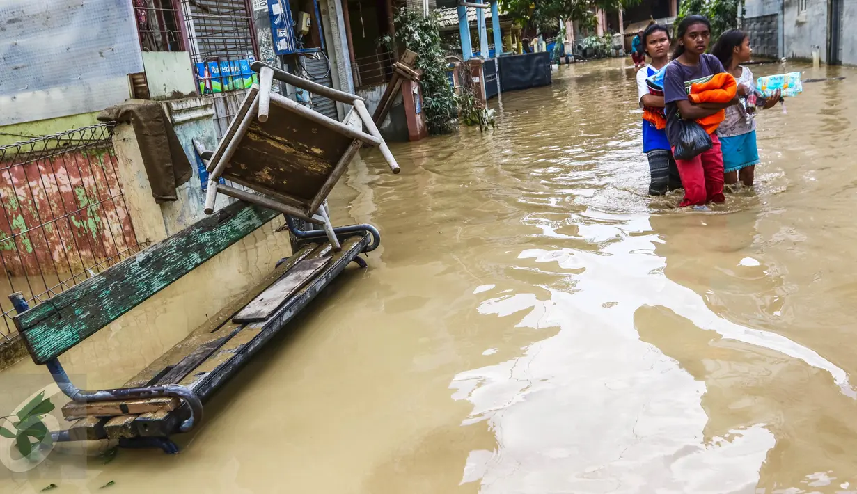 Sejumlah anak perempuan melintasi banjir yang masih merendam komplek Pondok Gede Permai, Jatiasih, Bekasi, Jumat (22/4). Sejak banjir menerjang perumahan tersebut hanya ada sekitar 50 warga yang mau dievakuasi. (Liputan6.com/Fery Pradolo)