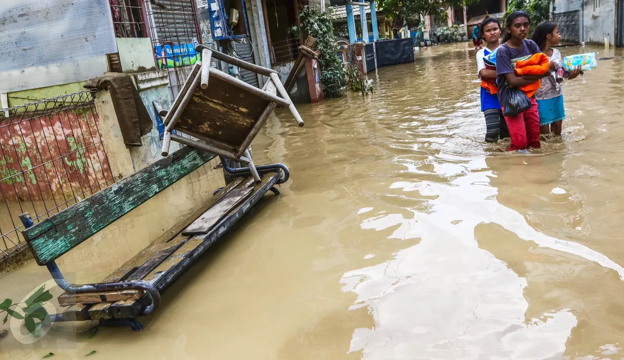 Sejumlah anak perempuan melintasi banjir yang masih merendam komplek Pondok Gede Permai, Jatiasih, Bekasi, Jumat (22/4). Sejak banjir menerjang perumahan tersebut hanya ada sekitar 50 warga yang mau dievakuasi. (Liputan6.com/Fery Pradolo)